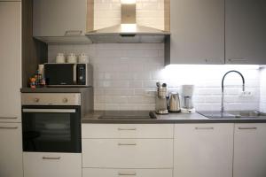 cocina con armarios blancos, fregadero y microondas en New & Luxury apartment Tony, en Split