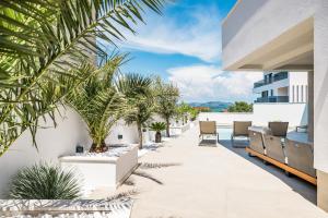 an outdoor patio with chairs and palm trees on a building at Villa Corus in Murter