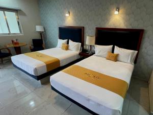 Cette chambre comprend 2 lits et une table. dans l'établissement Hotel Maioris Bellavista, à Culiacán
