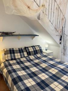 a bedroom with a blue and white plaid bed and stairs at Albamare apartment in Marettimo