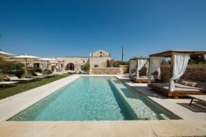 a swimming pool with chairs and a house at Agriturismo Alonì Costarella Masseria in Borgagne