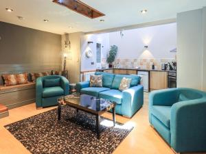 Una sala de estar con dos sillas azules y una mesa. en 2 The Old Coach House, en Ambleside