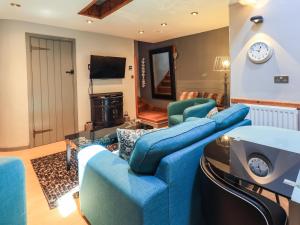 ein Wohnzimmer mit einem blauen Sofa und Stühlen in der Unterkunft 2 The Old Coach House in Ambleside