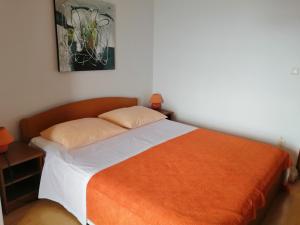 a bedroom with a bed with an orange blanket at Apartmani Grgo in Živogošće
