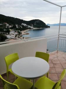 een tafel en stoelen op een balkon met uitzicht op het water bij Apartmani Grgo in Živogošće
