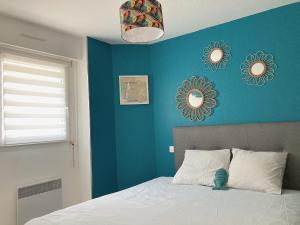 a bedroom with a blue wall with a bed and two mirrors at Au Ti Menhir * 2 à 4 vacanciers * Piscine * WIFI in Carnac