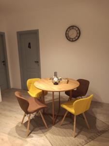 a dining room table with chairs and a clock on the wall at Villa Artisan in Sremski Karlovci