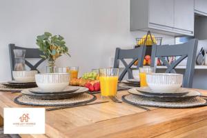a wooden table with plates and cups of orange juice at Harvey's Yard Luxury Home-St Ives-Beach-Parking 5* in Hayle