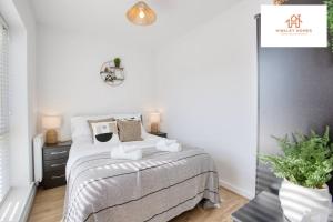 a white bedroom with a bed and a plant at Harvey's Yard Luxury Home-St Ives-Beach-Parking 5* in Hayle