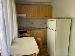 a kitchen with a table and a white refrigerator at Exohi apartments in Nea Vrasna