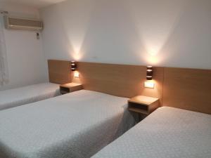 2 Betten in einem Zimmer mit Beleuchtung in der Unterkunft Restaurante e Residencial O Resineiro in Vidago