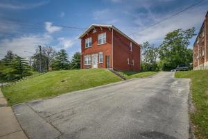 un gran edificio de ladrillo rojo en una colina con césped en Convenient Jennings Apartment, 12 Mi to St Louis!, 