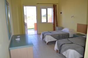 una camera d'albergo con due letti e un tavolo di To Akrogiali a Fánai