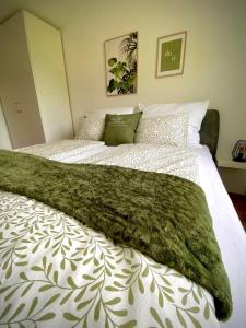 un grande letto con una coperta verde sopra di Apartment Ferienwohnung DAS UNTERACH am Attersee a Unterach am Attersee