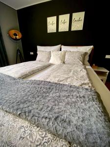uma cama com um edredão cinzento e almofadas em Apartment Ferienwohnung DAS UNTERACH am Attersee em Unterach am Attersee