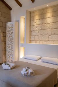 1 dormitorio con 2 camas, toallas y espejo en Agriturismo Masseria Costarella, en Borgagne