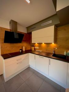 een keuken met witte kasten, een wastafel en een tv bij Apartment Ferienwohnung DAS UNTERACH am Attersee in Unterach am Attersee