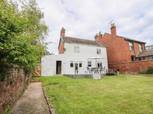 an exterior view of a white house with a brick wall at The Ferns in Ludlow