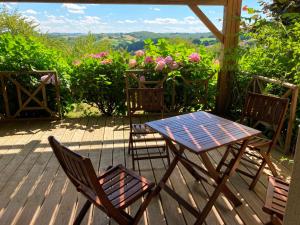 a table and chairs on a deck with flowers at LE CLOS DE BAJARDAN in Couloumé-Mondébat