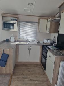 a small kitchen with white cabinets and a sink at Seaside Jollys in Blue Anchor