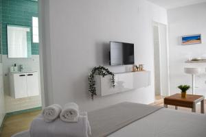 um quarto branco com uma cama e uma televisão na parede em Loft La Abuela em Vejer de la Frontera