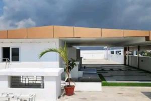 a white house with a palm tree in front of it at Luxurious Apartment with a pool and gym near Trivandrum railway station in Trivandrum