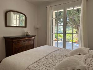 a bedroom with a bed and a mirror and a window at Les Stoechades in Rayol-Canadel-sur-Mer