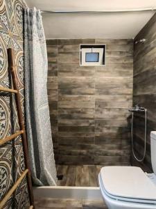 a bathroom with a toilet and a television on the wall at The Cozy Nest in Rhodes town in Rhodes Town