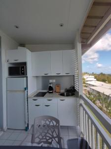una cucina con armadi bianchi e un balcone di Un petit joyau a Le Diamant