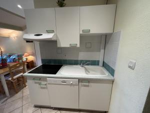 a kitchen with white cabinets and a sink at vue mer Studio 2/3 pers 1 bed + 1 cot in Farinole +4 photos