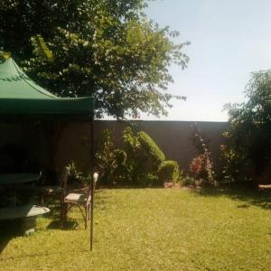 un cortile con una sedia e un ombrellone nell'erba di Samkab Legacy & comfort Ndeke (airport) a Lusaka