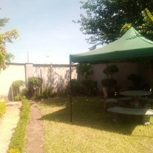 a table and a green umbrella in a yard at Samkab Legacy & comfort Ndeke (airport) in Lusaka