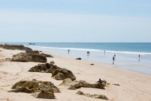 a beach with people in the water and people in the ocean at Bayside Salgados in Albufeira