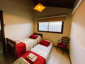 Habitación con 2 camas, silla y ventana en Casa Roca en Ushuaia