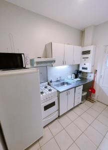 una cocina con armarios blancos y un horno de fogón blanco en Casa Roca en Ushuaia