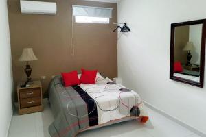 1 dormitorio con cama con almohadas rojas y espejo en Malecon Rooms y Hotel en Santo Domingo