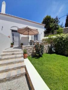 a white house with an umbrella in the yard at Tatiana's House in Spetses