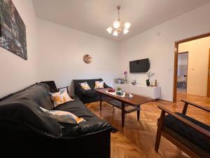 a living room with a black couch and a table at DALIA Apartment & Room in Mostar