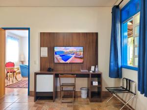 Habitación con escritorio y TV en la pared. en Pousada Ouro Preto de Bonito en Bonito