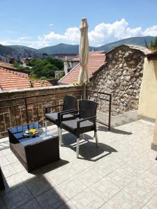a patio with an umbrella and two chairs and a table at DALIA Apartment & Room in Mostar