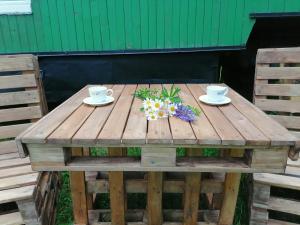 una mesa de madera con dos tazas y flores. en Šťastná Maringotka, 