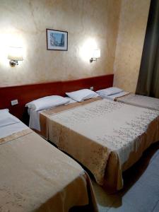 a hotel room with two beds and two lamps at Hotel Ferrari in Rome