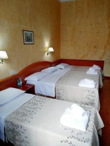 three beds in a hotel room with towels on them at Hotel Ferrari in Rome