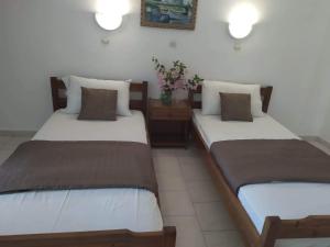 - 2 lits dans une chambre avec des fleurs sur une table dans l'établissement STUDIO ZOE, à Marmari