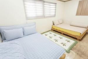 a small bedroom with two beds and a bench at Danaharu Guesthouse in Jeonju
