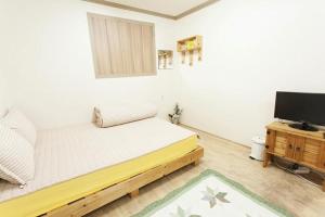 a bedroom with a bed and a flat screen tv at Danaharu Guesthouse in Jeonju