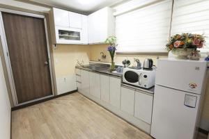 a kitchen with a white refrigerator and a microwave at Danaharu Guesthouse in Jeonju