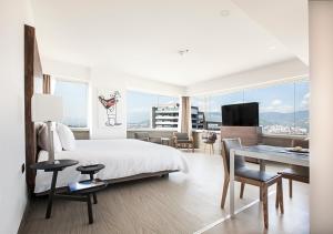 um quarto de hotel com uma cama, uma secretária e uma vista em Viaggio Medellín Grand Select em Medellín