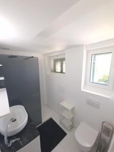 a white bathroom with a toilet and a sink at Apartments Eis in Baška
