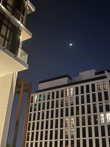 a tall building at night with the moon in the sky at Home 4U in Dubai Center in Dubai